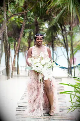 A bride walks down a beach pathway in a stunning modern dusty rose wedding dress.
