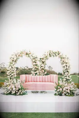 A blush pink sofa sits beneath a pair of romantic floral arches.