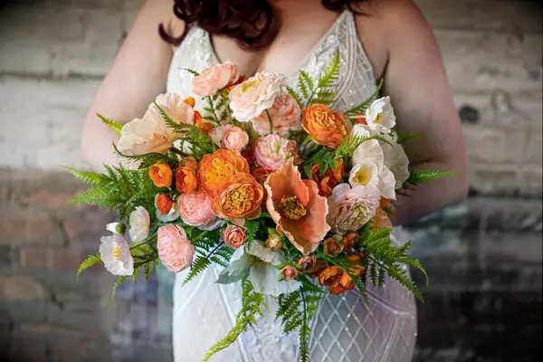 Bride holding a bunch of orange flowers