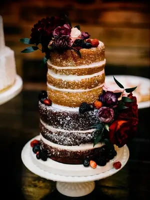 Naked rustic wedding cake with dark red flowers