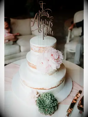 Semi-naked rustic wedding cake with white icing and pastel peonies with succulents
