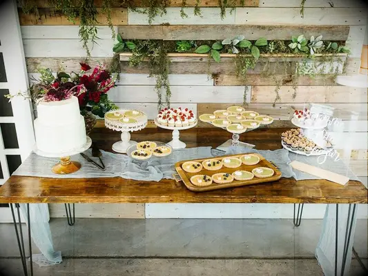 Rustic wood farmhouse dessert table with wedding cake, cupcakes and mini pies