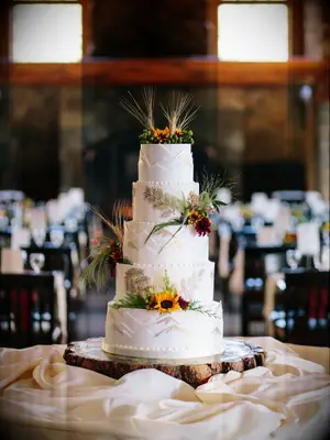Five-tier rustic wedding cake with wildflower accents and grassy palms