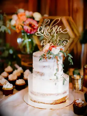 Two-tier semi-naked rustic wedding cake with glam gold cake topper and fresh flowers