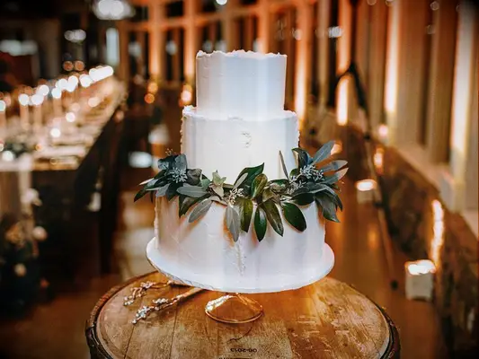 Simple rustic wedding cake with white icing and garland of eucalyptus leaves