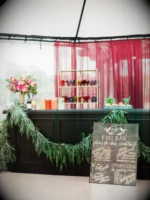 wedding cocktail bar decorated with greenery garland and colorful flower arrangement