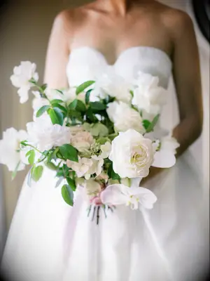 bride holding classic garden style wedding bouquet with white roses and greenery