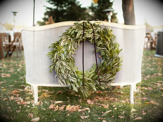 the back of a gray velvet settee decorated with greenery wreath