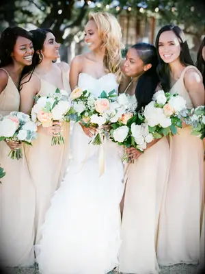 bride stands with bridesmaids holding white and yellow bouquets