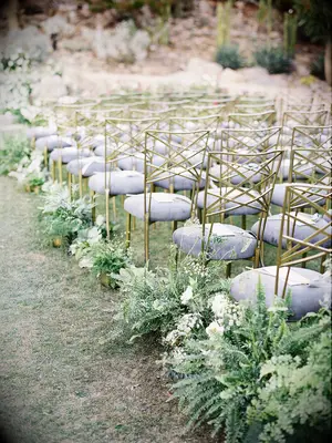 outdoor wedding ceremony aisle with gold chameleon chairs and fern aisle markers