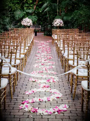 outdoor wedding ceremony venue with cobblestone aisle decorated with pink rose petals in swirled pattern