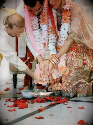 bride and groom performing fire ritual at hindu wedding while wearing floral garlands