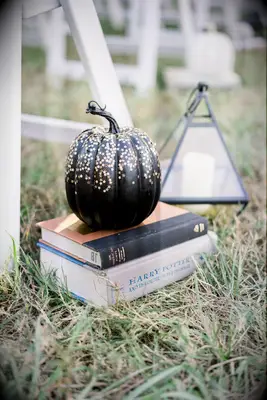 Black pumpkin decorated with gold stars at a Halloween wedding