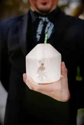 Waiter holding signature cocktail in fresh coconut