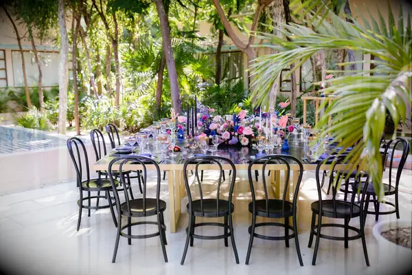Glam beach reception with black bentwood chairs and gold table