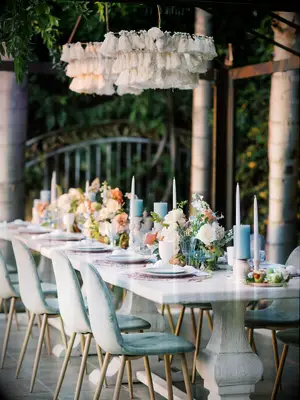 Beach reception tablescape with blue velvet chairs, blue candles and white cloth chandeliers