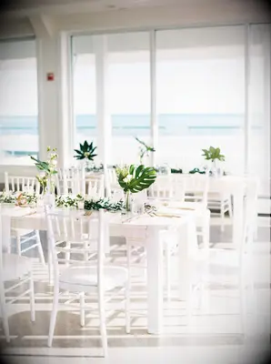 All-white reception decor with tropical leaf centerpieces