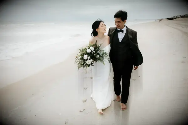 Couple walking down the beach in formal wedding attire