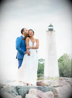 Couple kissing on rocks on the beach by lighthouse