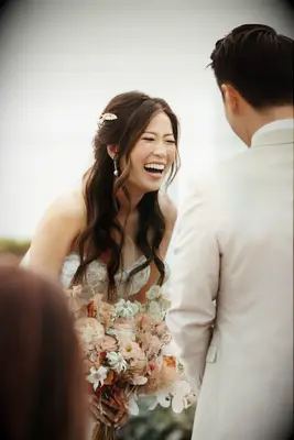 Bride with beauty waves laughing during vow exchange