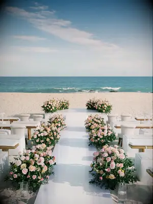Beach wedding ceremony with white benches and rose aisle decorations 