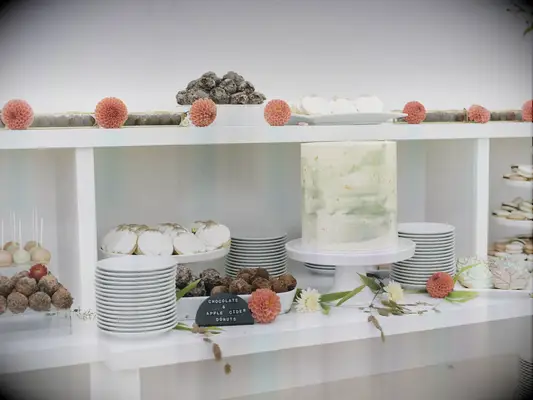 Single tier wedding cake on minimalist display with wedding desserts