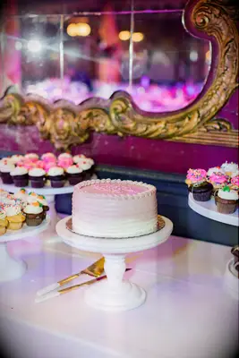 Single-Tier, White-to-Pink Ombre Wedding Cake on Dessert Table With Cupcakes