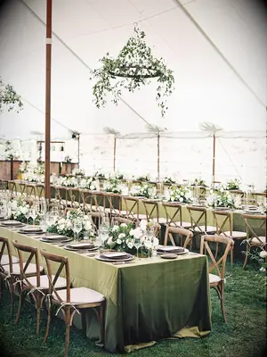 tented wedding reception with long banquet tables covered in olive green linens