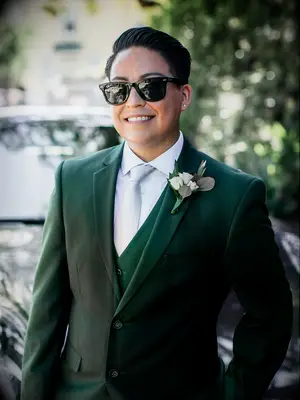 bride wears three-piece emerald green suit with wayfarer sunglasses