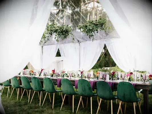 long wedding banquet table with emerald green velvet chairs