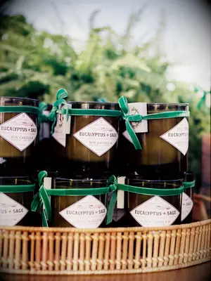 stack of wedding candle favors in glass jars wrapped with emerald green ribbons