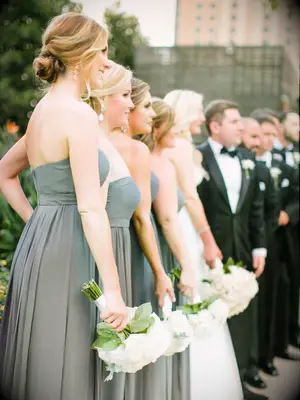 bridesmaids wearing strapless sage green gowns stand at wedding ceremony altar 