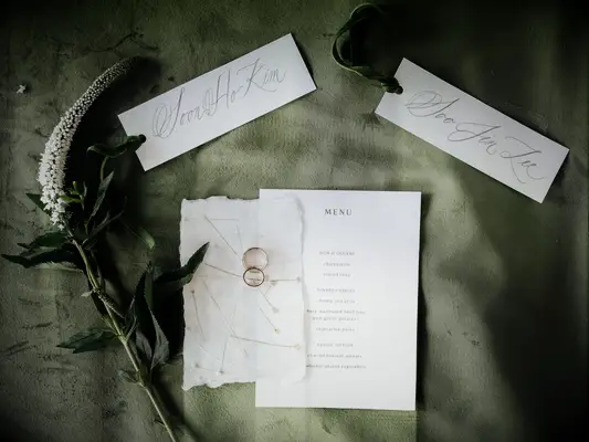 wedding stationery flatlay with invitations decorated with olive green calligraphy