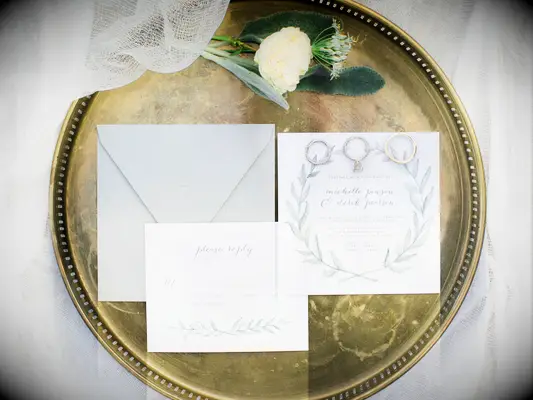 classic wedding invitation with sage green laurel wreath motif and matching envelope