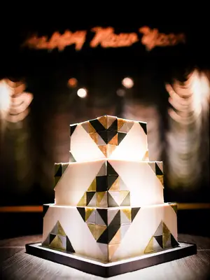 Square three-tier white wedding cake with black, gold and silver Art Deco pattern