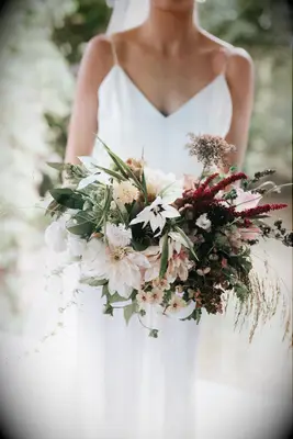 Bride holds a beautiful bouquet of cafe au lait dahlias and greenery. 