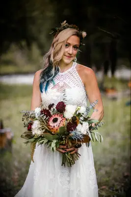 Bride wears a flower crown in her hair and holds a bouquet of dahlias. 