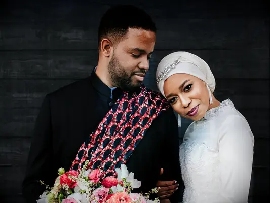 bride in hijab hugging groom during wedding portraits