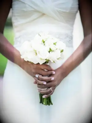 A bride holds a petite white wedding bouquet.