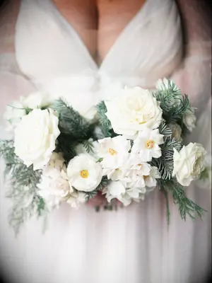 This petite white wedding bouquet is perfect for a winter wedding, with shades of dusky green and bright bursts of yellow.