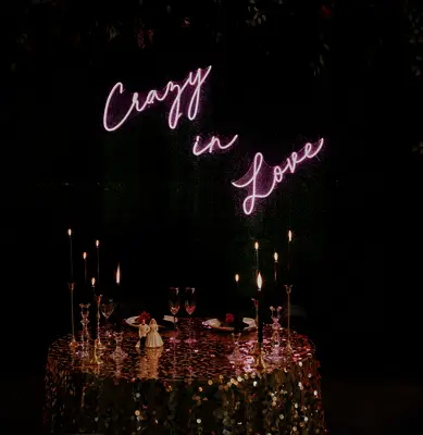 modern sweetheart table decor with gold sequined tablecloth and pink neon sign backdrop that says crazy in love
