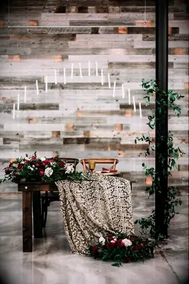 unique sweetheart table idea for harry potter wedding decorated with gold patterned tablecloth, red flowers and floating candles above the table