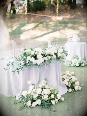 elegant wedding sweetheart table idea with gray tablecloth, gray taper candles and white rose oversized centerpiece with greenery
