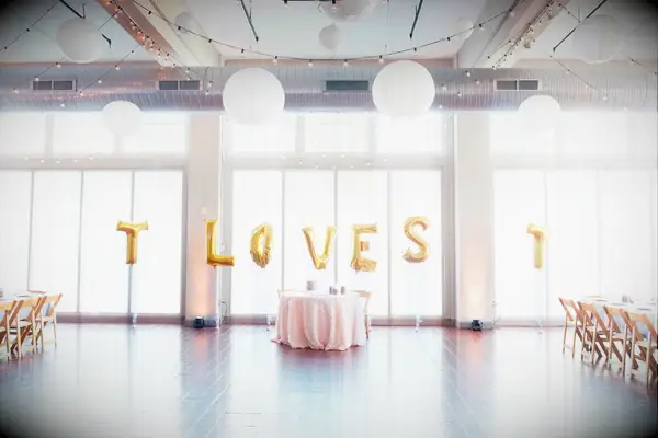 whimsical wedding sweetheart table idea with giant gold balloons in the background spelling T loves T
