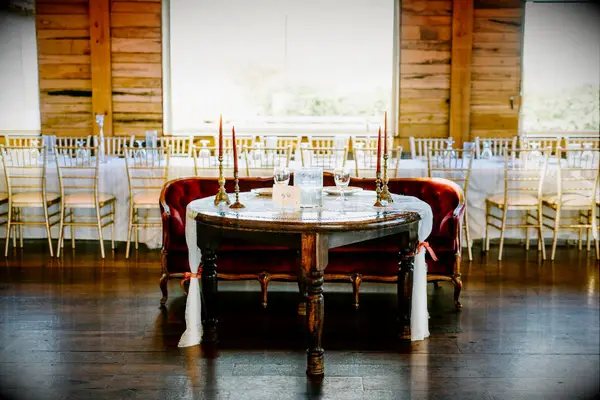 simple wedding sweetheart decor with red velvet antique loveseat, wooden table and brass candlesticks