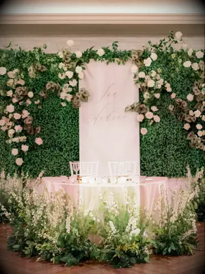 romantic wedding sweetheart table decor with greenery wall, white flowers and custom backdrop with couple