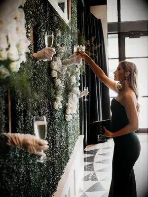 wedding guest takes a glass of champagne from a server holding drinks through an opening in the wall