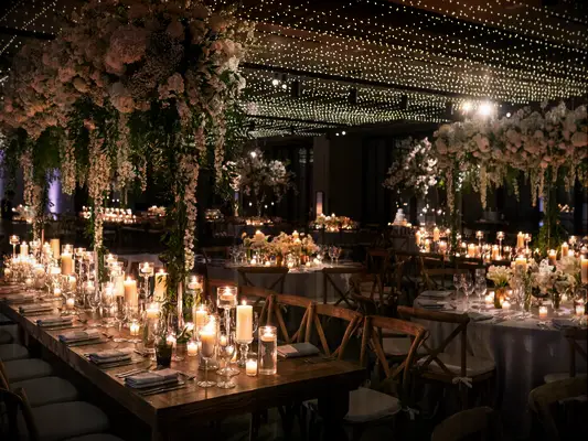 indoor wedding reception with tall centerpieces above long tables lined with candles down the center