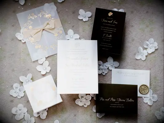 luxury wedding invitations embossed with gold calligraphy text against white background with black insert cards, vellum envelope and gold wax seal stamp