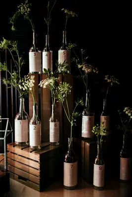 wedding decor idea on a budget seating chart display with wine bottles and stems of queen anne